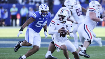 Oct 12, 2024; Provo, Utah, USA; Arizona Wildcats quarterback Noah Fifita (11) is rushed by Brigham Young Cougars linebacker Siale Esera (54) during the fourth quarter at LaVell Edwards Stadium. Mandatory Credit: Rob Gray-Imagn Images