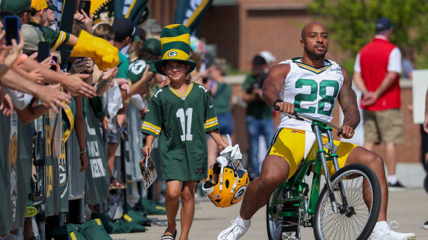 Green Bay Packers running back A.J. Dillon rides a bicycle to practice.