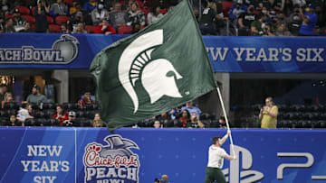 Dec 30, 2021; Atlanta, GA, USA; Michigan State Spartans cheerleader runs with a flag after a touchdown against the Pittsburgh Panthers in the second half during the 2021 Peach Bowl at Mercedes-Benz Stadium. Mandatory Credit: Brett Davis-Imagn Images