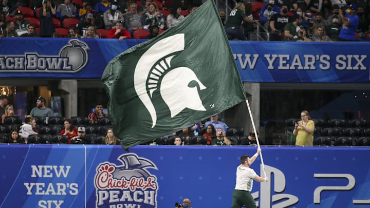 Dec 30, 2021; Atlanta, GA, USA; Michigan State Spartans cheerleader runs with a flag after a touchdown against the Pittsburgh Panthers in the second half during the 2021 Peach Bowl at Mercedes-Benz Stadium. Mandatory Credit: Brett Davis-Imagn Images