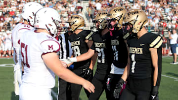 Captains of Mishawaka and Penn meet at the 50 yard line for the coin toss.