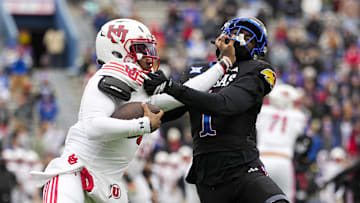 Nov 28, 2025; Lawrence, Kansas, USA; Utah Utes quarterback Devon Dampier (4) stiff arms Kansas Jayhawks linebacker Bangally Kamara (1) during the second half at David Booth Kansas Memorial Stadium. Mandatory Credit: Jay Biggerstaff-Imagn Images