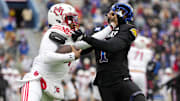 Nov 28, 2025; Lawrence, Kansas, USA; Utah Utes quarterback Devon Dampier (4) stiff arms Kansas Jayhawks linebacker Bangally Kamara (1) during the second half at David Booth Kansas Memorial Stadium. Mandatory Credit: Jay Biggerstaff-Imagn Images