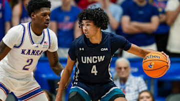 Nov 19, 2024; Lawrence, Kansas, USA; North Carolina-Wilmington Seahawks guard Nolan Hodge (4) dribbles the ball against Kansas Jayhawks guard AJ Storr (2) during the second half at Allen Fieldhouse. Mandatory Credit: Jay Biggerstaff-Imagn Images