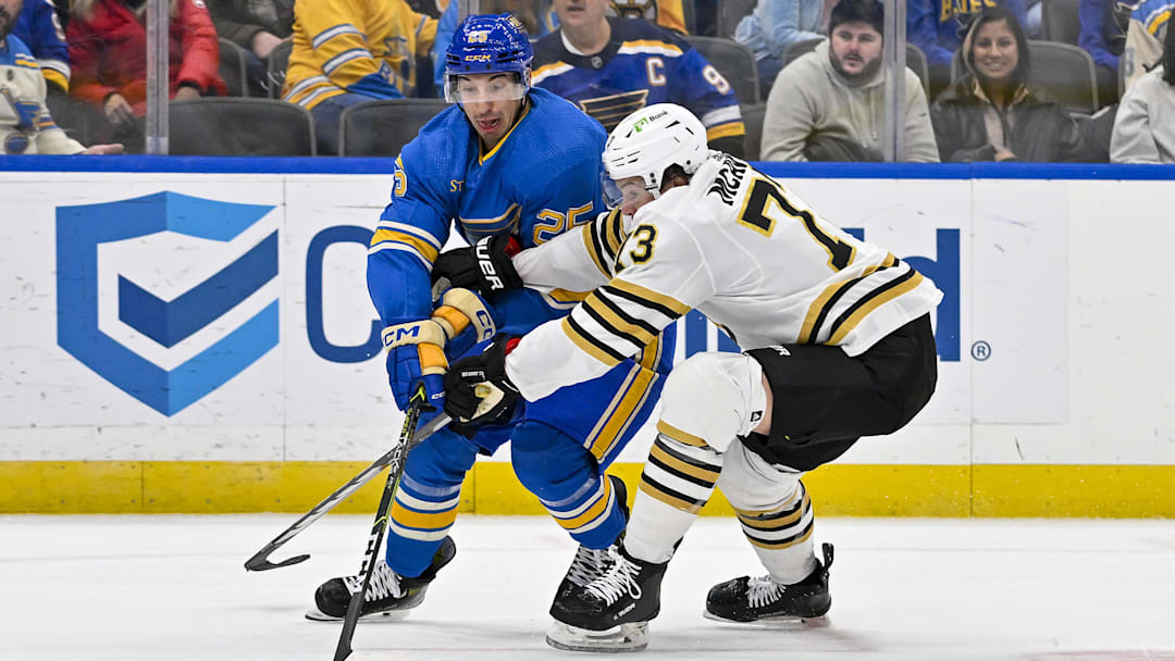 Jan 13, 2024; St. Louis, Missouri, USA;  St. Louis Blues center Jordan Kyrou (25) and Boston Bruins defenseman Charlie McAvoy (73) battle for the puck during the second period at Enterprise Center. Mandatory Credit: Jeff Curry-Imagn Images