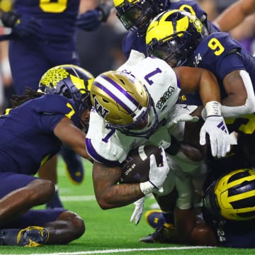 Jan 8, 2024; Houston, TX, USA; Washington Huskies running back Dillon Johnson (7) is tackled by Michigan Wolverines defensive back Makari Paige (7) and defensive back Rod Moore (right) during the second quarter in the 2024 College Football Playoff national championship game at NRG Stadium. Mandatory Credit: Mark J. Rebilas-USA TODAY Sports