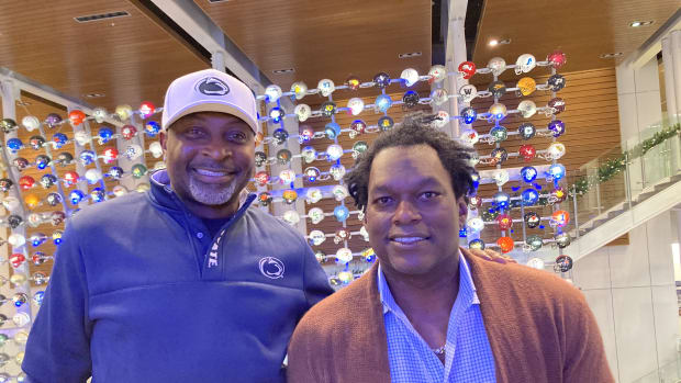 O.J. McDuffie stands next to LaVar Arrington in front of a display of football helmets at the College Football Hall of Fame.