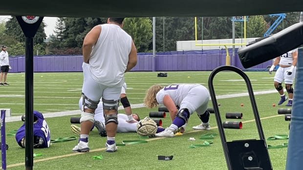 Will Rogers is flat on his back as offensive linemen Gaard Memmelaar and Landen Hatchett stretch him out.