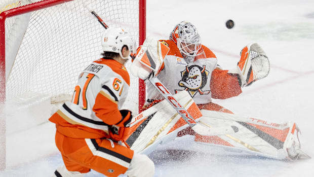 Hockey goalie in white uniform attempts to save shot on goal