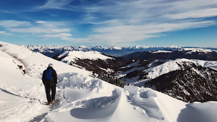 Hiker standing on a snowy summit Hiker standing on a snowy summit