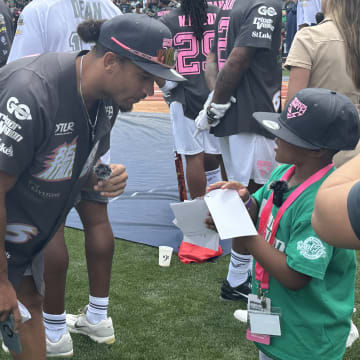 Eagles safety Sydney Brown signs an autograph for a young fan during DeVonta Smith's celebrity softball game on June 29, 2024. 