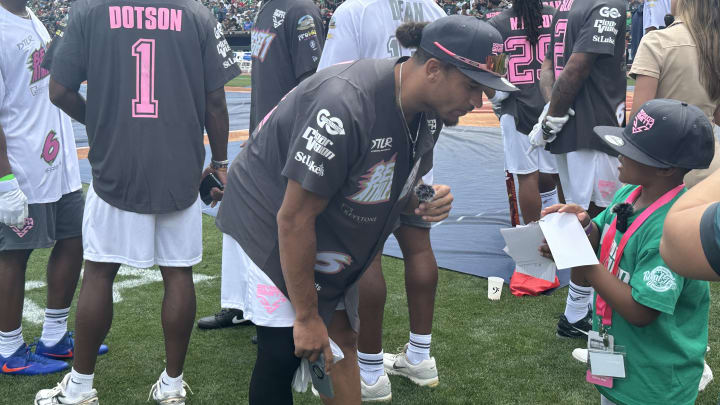 Eagles safety Sydney Brown signs an autograph for a young fan during DeVonta Smith's celebrity softball game on June 29, 2024. 