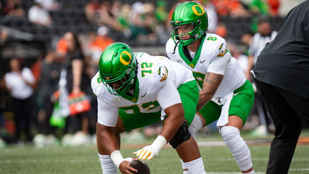 Oregon offensive lineman Iapani Laloulu snaps the ball to Oregon quarterback Dillon Gabriel 