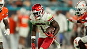 Oct 17, 2025; Miami Gardens, Florida, USA; Louisville Cardinals running back Isaac Brown (1) carries the football against Miami Hurricanes linebacker Mohamed Toure (1) and linebacker Wesley Bissainthe (31) during the first quarter at Hard Rock Stadium. Mandatory Credit: Sam Navarro-Imagn Images