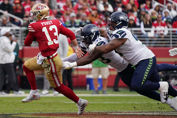 San Francisco 49ers quarterback Brock Purdy (13) scrambles away from Seattle Seahawks linebacker Boye Mafe (53).
