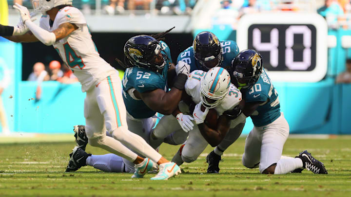 Sep 8, 2024; Miami Gardens, Florida, USA; Miami Dolphins running back Raheem Mostert (31) runs with the football against Jacksonville Jaguars defensive tackle DaVon Hamilton (52), linebacker Yasir Abdullah (56) and cornerback Montaric Brown (30) during the fourth quarter at Hard Rock Stadium. Mandatory Credit: Sam Navarro-Imagn Images