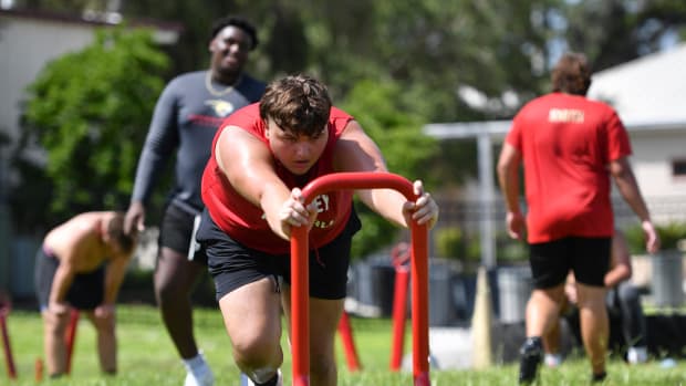 Ethan Salata pushes a weighted sled during the morning workout. Cardinal Mooney High football players participate