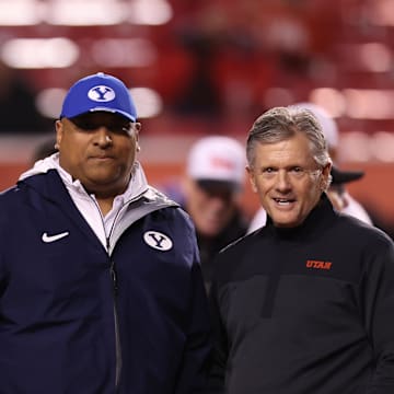 Brigham Young Cougars head coach Kalani Sitake (left) and Utah Utes head coach Kyle Whittingham speak before a game at Rice-Eccles Stadium.