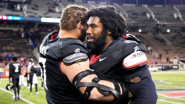 Cincinnati Bearcats offensive lineman Luke Kandra (67), left, and Cincinnati Bearcats defensive end Jowon Briggs (0) embrace after losing the NCAA college football game between the Cincinnati Bearcats and Kansas Jayhawks on Saturday, Nov. 25, 2023, at Nippert Stadium in Cincinnati. Kansas won 49-16.