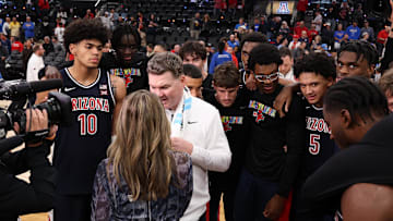 Nov 14, 2025; Inglewood, California, USA;  Arizona Wildcats head coach Tommy Lloyd surrounds by his players as he is taking a post game interview after defeating the UCLA Bruins 69-65 at Intuit Dome. Mandatory Credit: Kiyoshi Mio-Imagn Images