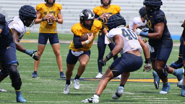 WVU QB Garrett Greene runs through the middle of the defensive while LB Josiah Trotter (40) closes in. 