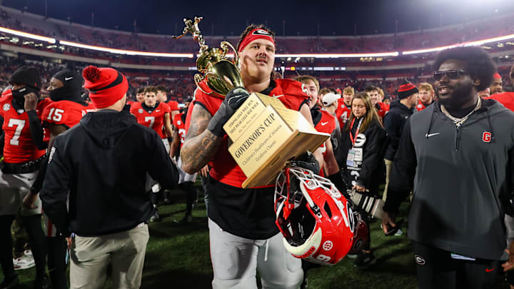 Nov 29, 2024; Athens, Georgia, USA; Georgia Bulldogs offensive lineman Tate Ratledge (69) holds the Governor’s Cup with running back Cash Jones (32) after a victory over the Georgia Tech Yellow Jackets in eight overtimes at Sanford Stadium. Mandatory Credit: Brett Davis-Imagn Images