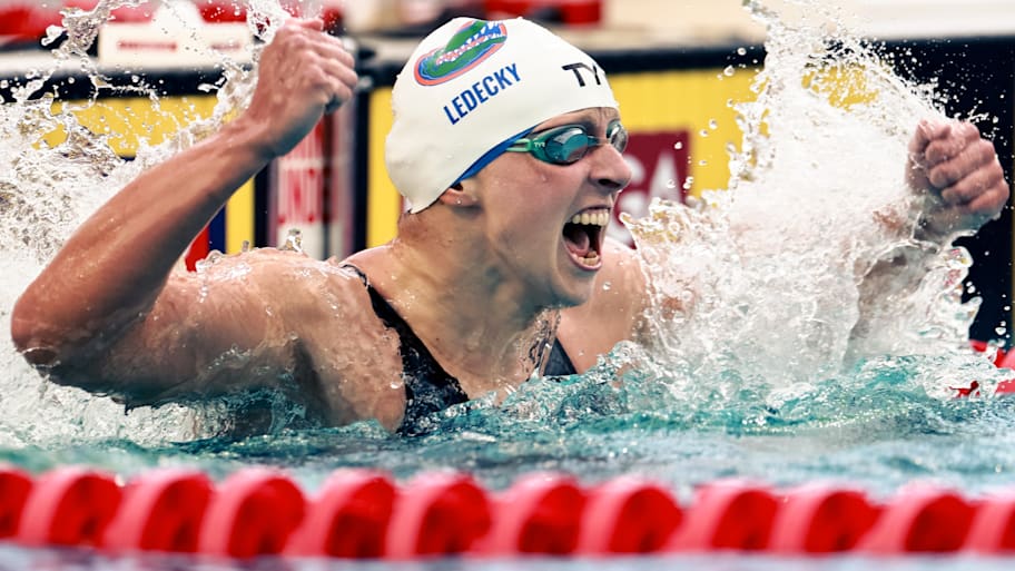 Katie Ledecky celebrates after finishing a race by slapping the water.