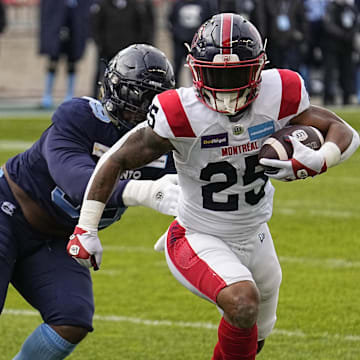 Nov 13, 2022; Toronto, Ontario, CAN; Montreal Alouettes running back Walter Fletcher (25) tries to outrun Toronto Argonauts defensive lineman Dewayne Hendrix (99) on a rushing play during the first half at BMO Field. Mandatory Credit: John E. Sokolowski-Imagn Images