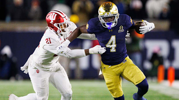 Notre Dame running back Jeremiyah Love (4) runs the ball past Indiana linebacker Rolijah Hardy during a CFP game.