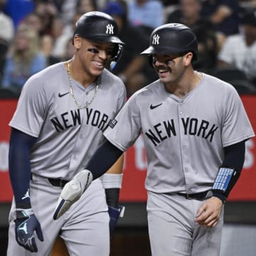 Sep 2, 2024; Arlington, Texas, USA; New York Yankees catcher Austin Wells (right) and center fielder Aaron Judge (left) laugh at home plate as they both score on a ground rule double hit by first baseman Anthony Rizzo (not pictured) during the sixth inning at Globe Life Field. Mandatory Credit: Jerome Miron-USA TODAY Sports