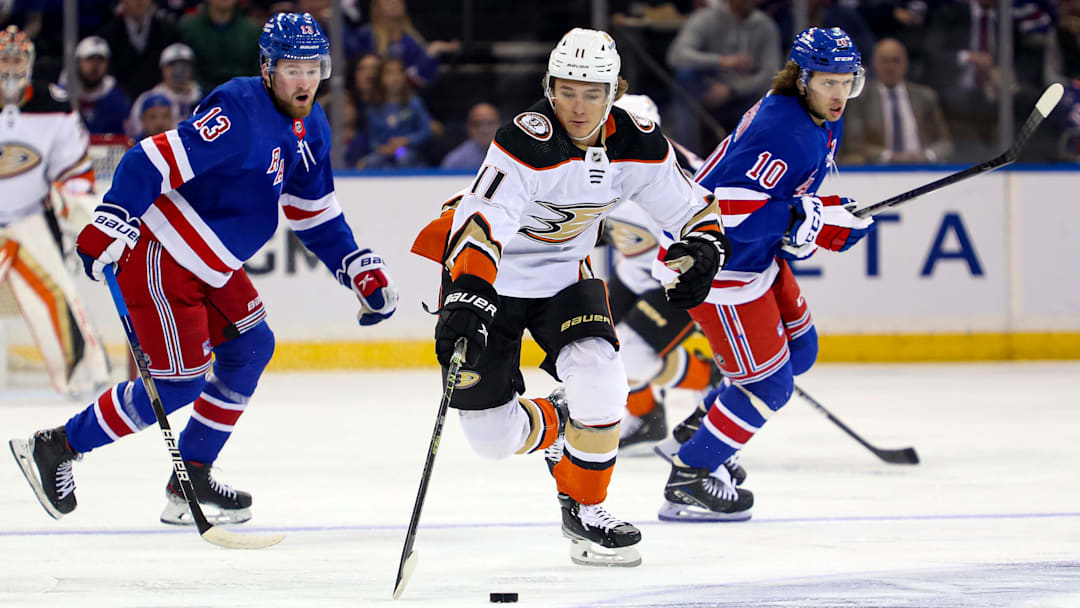 Oct 17, 2022; New York, New York, USA; Anaheim Ducks center Trevor Zegras (11) reaches for the puck in front of New York Rangers left wing Alexis Lafreniere (13) and New York Rangers left wing Artemi Panarin (10) during the first period at Madison Square Garden. Mandatory Credit: Danny Wild-Imagn Images