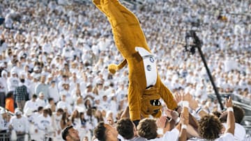 The Nittany Lion mascot does a front flip with some help from the Penn State cheerleaders during a White Out game