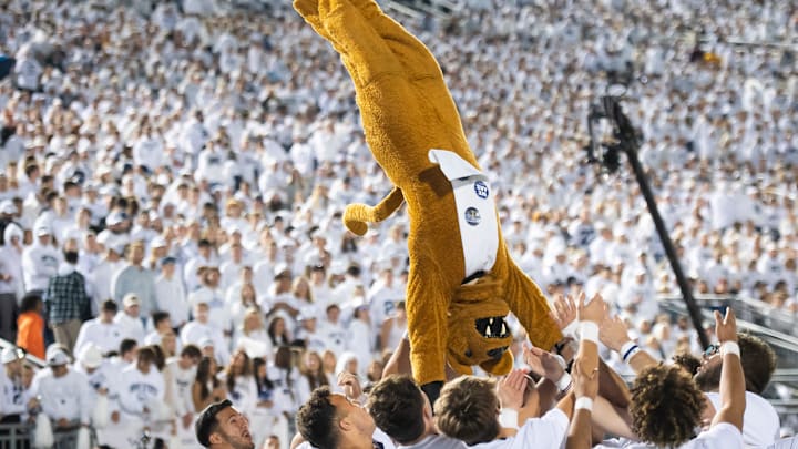 The Nittany Lion mascot does a front flip with some help from the Penn State cheerleaders during a White Out game