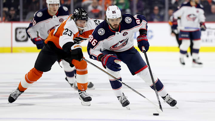 Blue Jackets forward Kirill Marchenko shields the puck from a Flyers back-checker. 