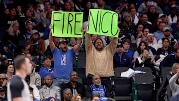 Two fans holding "Fire Nico" signs at a Dallas Mavericks game