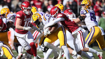Nov 12, 2022; Fayetteville, Arkansas, USA; LSU Tigers running back Noah Cain (21) is tackled by Arkansas Razorbacks defensive back Hudson Clark (17) and linebacker Bumper Poole (10) during the second quarter at Donald W. Reynolds Razorback Stadium. Mandatory Credit: Nelson Chenault-Imagn Images