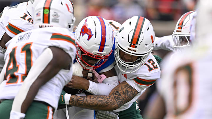 Nov 1, 2025; Dallas, Texas, USA;  SMU Mustangs quarterback Kevin Jennings (7) is sacked by Miami Hurricanes defensive lineman Marquise Lightfoot (12) during the second quarter at Gerald J. Ford Stadium. Mandatory Credit: Jerome Miron-Imagn Images