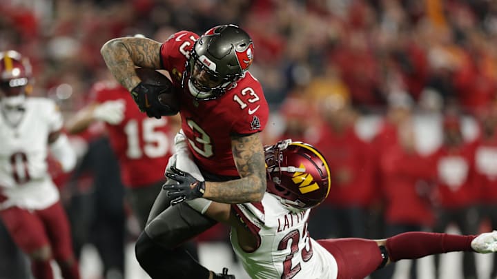 Jan 12, 2025; Tampa, Florida, USA; Tampa Bay Buccaneers wide receiver Mike Evans (13) is tackled by Washington Commanders cornerback Marshon Lattimore (23) during the second quarter of a NFC wild card playoff at Raymond James Stadium. Mandatory Credit: Nathan Ray Seebeck-Imagn Images