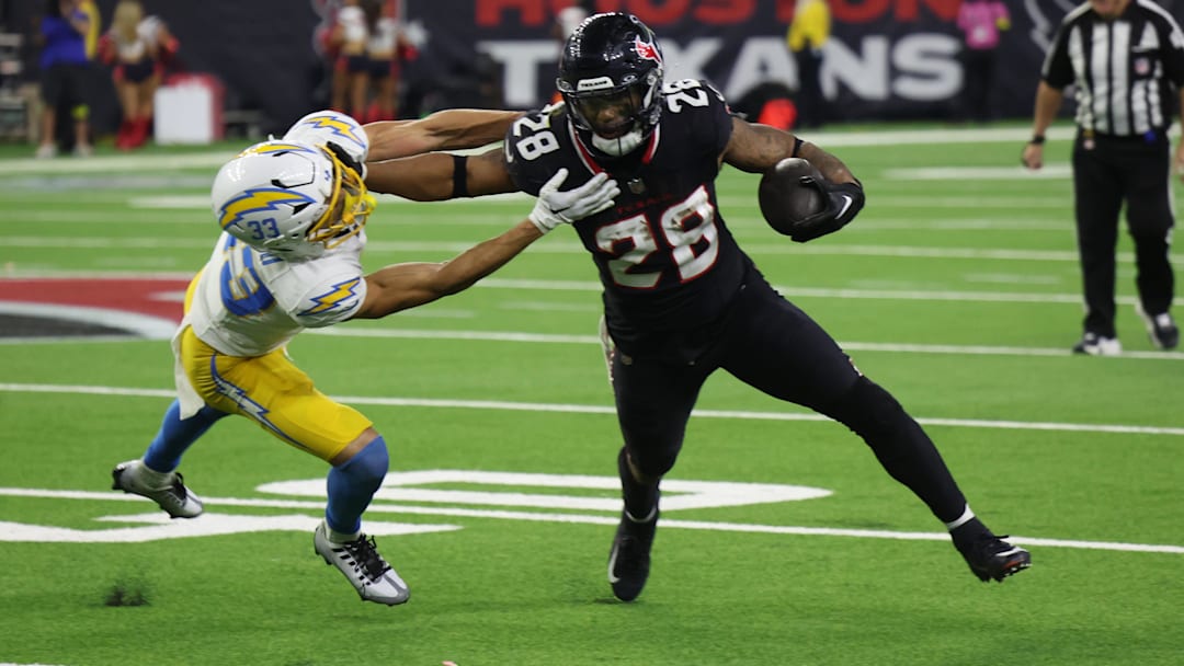 Jan 11, 2025; Houston, Texas, USA; -Los Angeles Chargers defensive back Deane Leonard (33) reaches for Houston Texans running back Joe Mixon (28) in the fourth quarter in an AFC wild card game at NRG Stadium. Mandatory Credit: Thomas Shea-Imagn Images