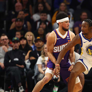 Dec 12, 2023; Phoenix, Arizona, USA; Golden State Warriors forward Jonathan Kuminga (00) against Phoenix Suns guard Devin Booker (1) at Footprint Center. Mandatory Credit: Mark J. Rebilas-Imagn Images