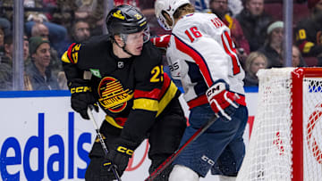 Jan 25, 2025; Vancouver, British Columbia, CAN; Vancouver Canucks defenseman Elias Pettersson (25) battles with Washington Capitals forward Taylor Raddysh (16) in the third period at Rogers Arena. Mandatory Credit: Bob Frid-Imagn Images