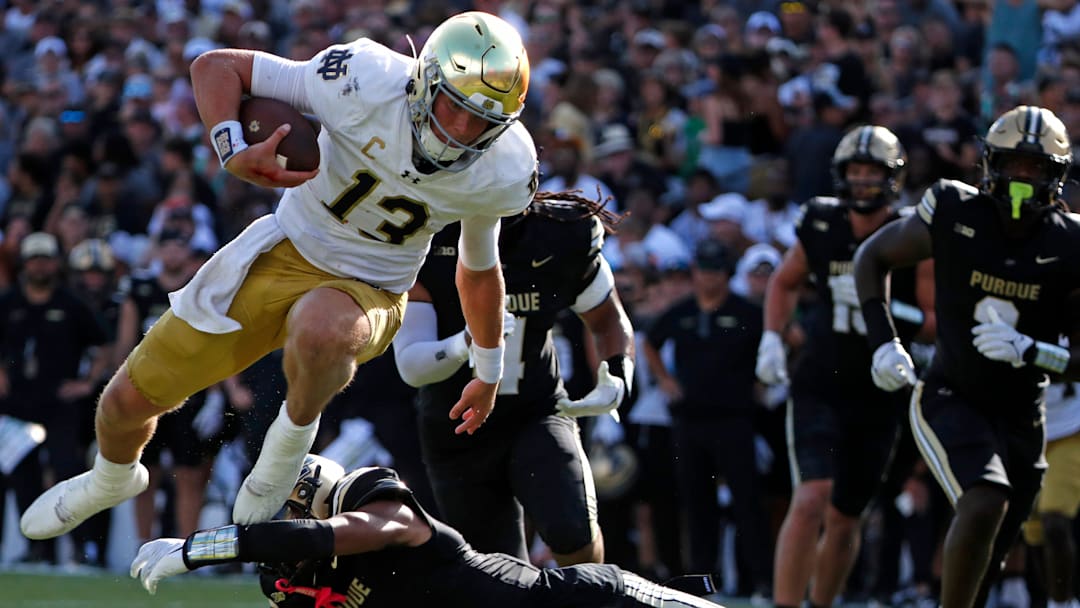 Notre Dame Fighting Irish quarterback Riley Leonard (13) breaks the tackle of Purdue Boilermakers defensive back Markevious Brown (1) Saturday, Sept. 14, 2024, during the NCAA football game at Ross-Ade Stadium in West Lafayette, Ind. Notre Dame Fighting Irish won 66-7.