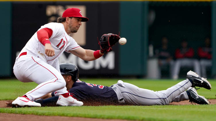 Cincinnati Reds shortstop Kyle Farmer (17) catches a throw as Cleveland Guardians right fielder slides.