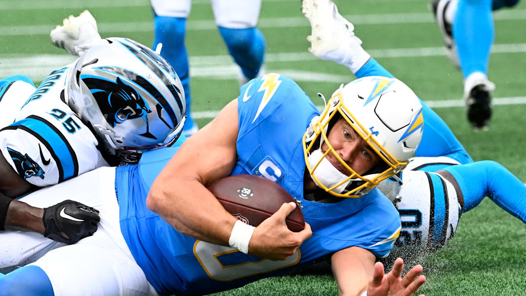 Sep 15, 2024; Charlotte, North Carolina, USA;  Los Angeles Chargers quarterback Justin Herbert (10) is tackled by Carolina Panthers safety Xavier Woods (25) and safety Jordan Fuller (20) in the second quarter at Bank of America Stadium. Mandatory Credit: Bob Donnan-Imagn Images