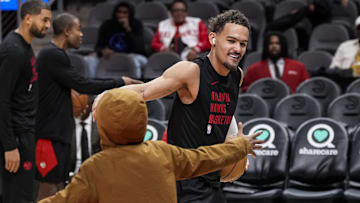 Atlanta Hawks guard Trae Young exchanges a handshake with a fan he passed the ball to on the court prior to the game at State Farm Arena