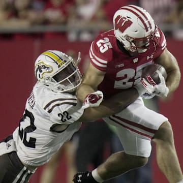 Aug 30, 2024; Madison, Wisconsin, USA;  Wisconsin running back Cade Yacamelli (25) is tackled by Western Michigan linebacker Boone Bonnema (22) during the first quarter of their game at Camp Randall Stadium. Mandatory Credit: Mark Hoffman-Imagn Images