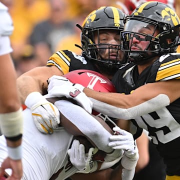 Sep 14, 2024; Iowa City, Iowa, USA; Troy Trojans running back Damien Taylor (3) is tackled by Iowa Hawkeyes defensive back Sebastian Castro (29) and defensive lineman Ethan Hurkett (49) as offensive lineman Tyler Cappi (65) looks on during the first quarter at Kinnick Stadium. Mandatory Credit: Jeffrey Becker-Imagn Images