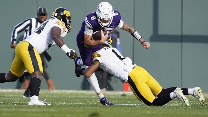 Nov 4, 2023; Chicago, Illinois, USA; Iowa Hawkeyes defensive back Xavier Nwankpa (1) tackles Northwestern Wildcats quarterback Brendan Sullivan (6) during the first half at Wrigley Field. Mandatory Credit: David Banks-Imagn Images