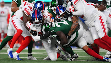Aug 24, 2024; East Rutherford, New Jersey, USA; New York Giants defensive tackle Casey Rogers (91) tackles New York Jets running back Israel Abanikanda (25) with help from a host of teammates during the first half at MetLife Stadium