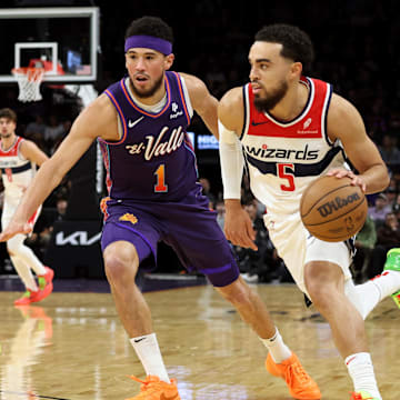 Dec 17, 2023; Phoenix, Arizona, USA; Washington Wizards guard Tyus Jones (5) drives to the net against Phoenix Suns guard Devin Booker (1) during the first quarter at Footprint Center. Mandatory Credit: Zachary BonDurant-Imagn Images